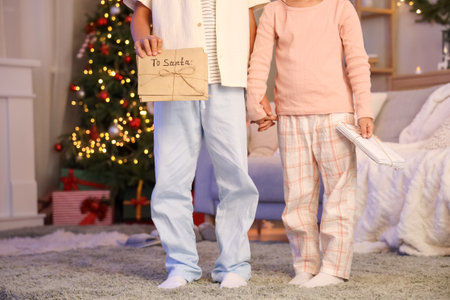 Cute little children in pajamas with letters to Santa at home on Christmas Eveの写真素材