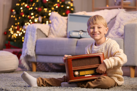 Cute little boy with retro radio receiver at home on Christmas Eveの写真素材