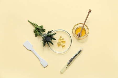 Laboratory glassware with plants and ingredients for preparing natural cosmetics on yellow backgroundの写真素材