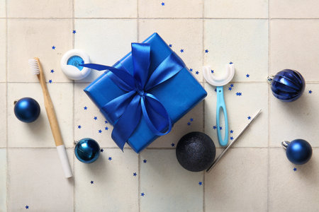 Composition with Christmas gift, dentist's tools and decorations on light tile backgroundの写真素材