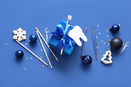 Composition with Christmas gift, dentist's tools and decorations on blue backgroundの写真素材