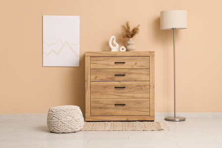 Comfortable pouf, lamp and wooden chest of drawers in living roomの写真素材
