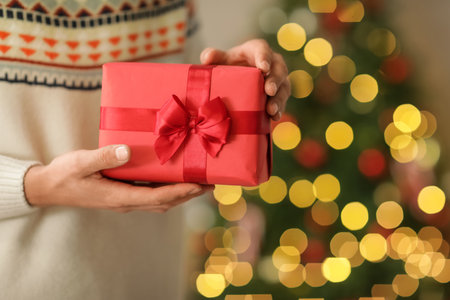 Man giving gift box near Christmas tree at home, closeupの写真素材