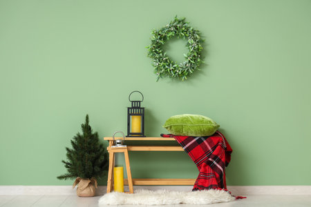 Bench with Christmas lanterns and fir tree near green wall in roomの写真素材