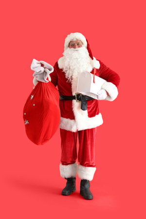 Santa Claus with Christmas bag and mailbox on red backgroundの写真素材