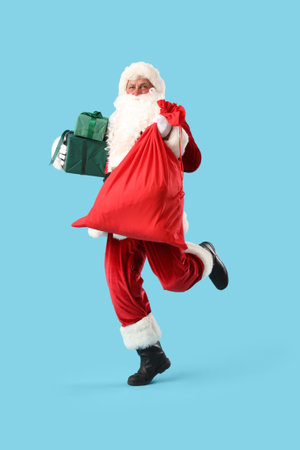 Santa Claus with bag and Christmas gift boxes running on blue backgroundの写真素材