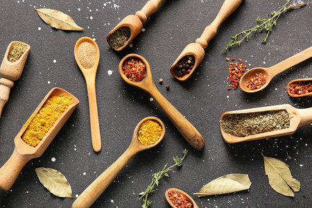 Wooden spoons and scoops with aromatic spices on dark backgroundの写真素材