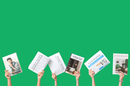 Female hands with different magazines and newspapers on green backgroundの写真素材