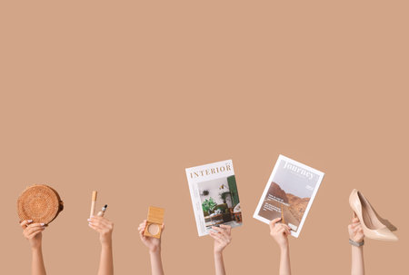 Female hands with different magazines, high heels, stylish bag and decorative cosmetics on brown backgroundの写真素材