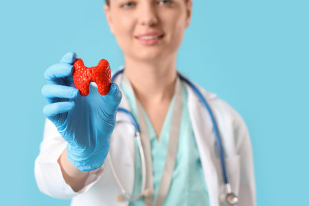 Female endocrinologist with thyroid gland model on blue background, closeupの写真素材