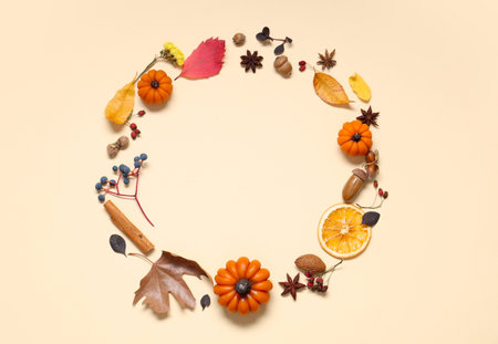 Frame made of candles in shape of pumpkin, autumn leaves and berries on beige backgroundの写真素材