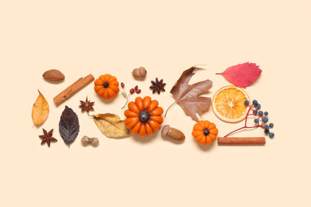 Candles in shape of pumpkin, autumn leaves and berries on beige background