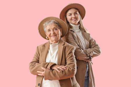 Happy senior woman and her granddaughter in autumn outfits on pink backgroundの写真素材