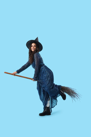 Young witch with broom on blue backgroundの写真素材