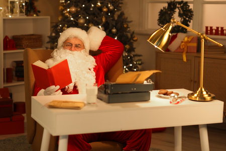 Santa Claus with typewriter and book preparing to writing Christmas story at nightの写真素材