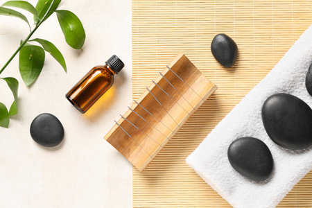 Acupuncture needles, oil, towel and spa stones on light backgroundの写真素材