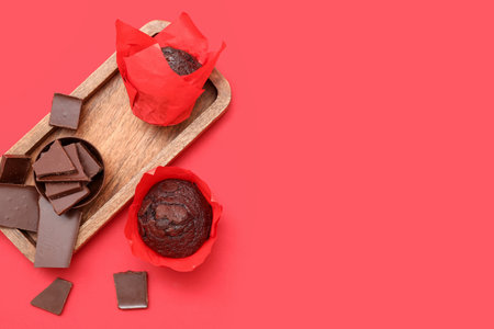 Wooden tray with tasty chocolate muffins on red backgroundの写真素材