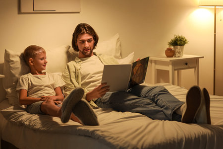Father and his little son reading bedtime story at home