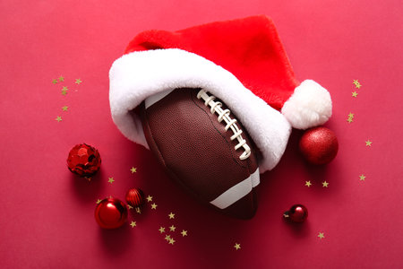 Composition with rugby ball, Santa hat and Christmas decorations on red backgroundの写真素材