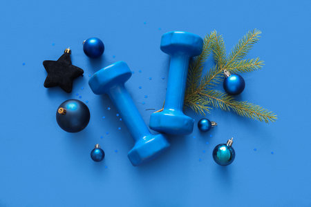 Composition with dumbbells and beautiful Christmas decorations on blue backgroundの写真素材