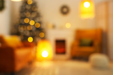 Blurred view of living room with fireplace, Christmas tree and glowing lamps in eveningの写真素材
