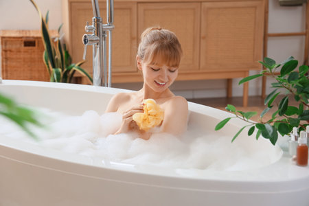Young woman taking bath with loofah and foam at home