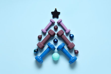 Christmas tree made of different dumbbells and decorations on color background