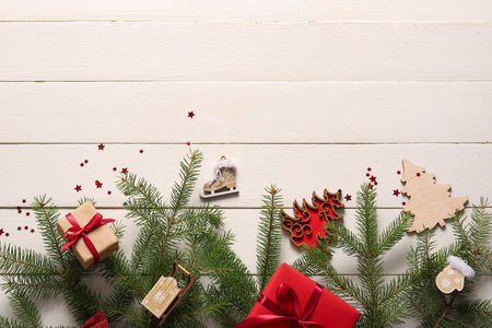 Fir branches with Christmas decorations and gift boxes on white wooden backgroundの写真素材