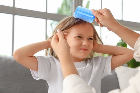 Mother combing her little daughter's hair with pediculosis at home, closeupの写真素材