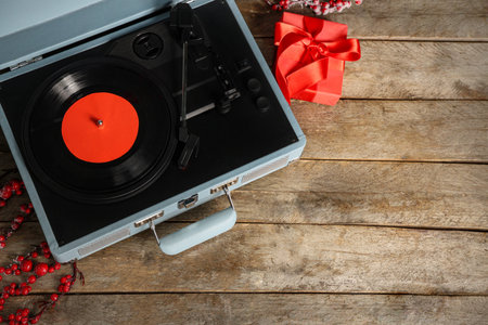 Vinyl record player with Christmas gift box and viburnum on wooden background