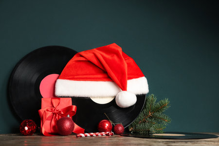 Vinyl discs with Santa hat, Christmas balls, fir branch and gift box on wooden tableの写真素材
