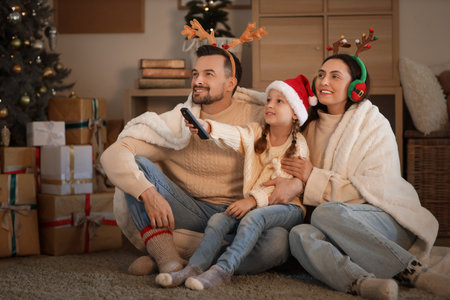 Little girl with her parents watching Christmas movie at homeの写真素材