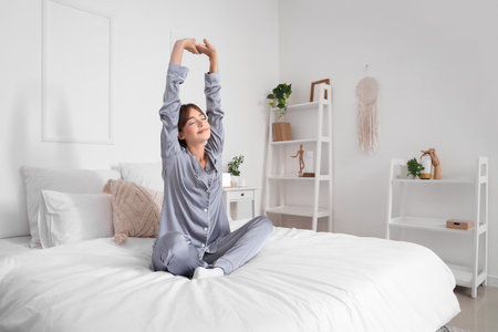 Morning of beautiful young woman stretching in bedroomの写真素材