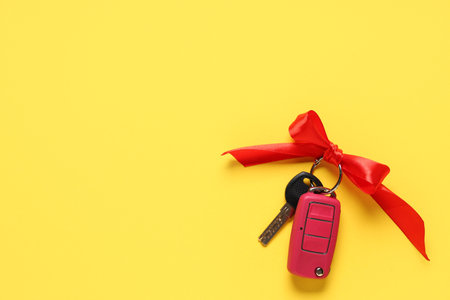 Gift keys of new car with bow on yellow backgroundの写真素材