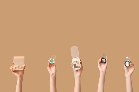 Female hands with different palettes of eyeshadows on brown backgroundの写真素材