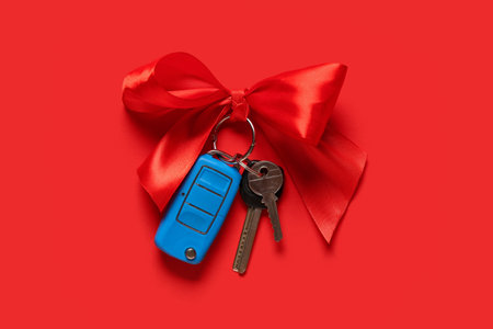 Gift keys of new car with bow on red backgroundの写真素材