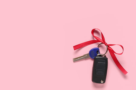Gift keys of new car with red bow on pink backgroundの写真素材