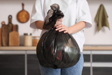 Woman with full bag of garbage in kitchen
