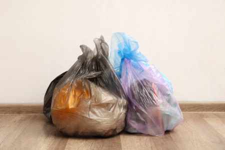 Full garbage bags near white wall