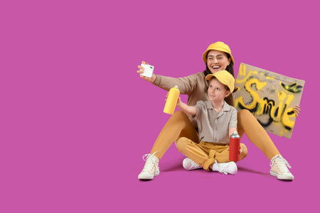 Little girl and her mother with graffiti taking selfie on purple background
