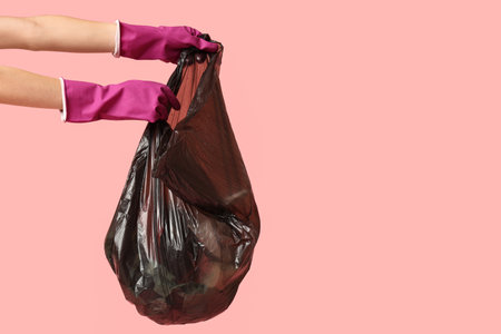 Woman with full garbage bag on pink backgroundの写真素材