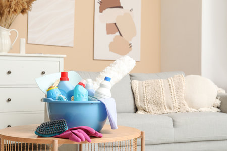 Basin with cleaning supplies on coffee table in living roomの写真素材