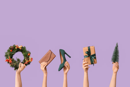 Many female hands with accessories, Christmas wreath, decorative fir and gift box on purple backgroundの写真素材
