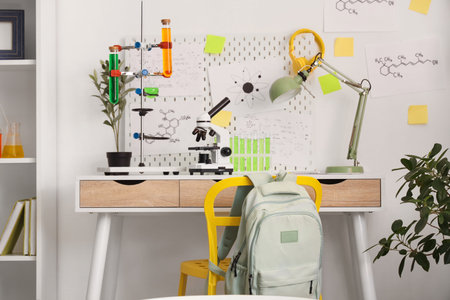 Modern microscope, chemical flasks on table and mood board in teenager's room