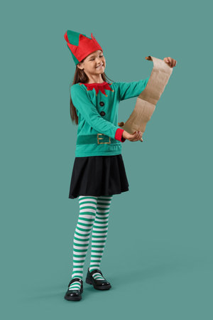 Little girl in elf costume with letter to Santa on green background