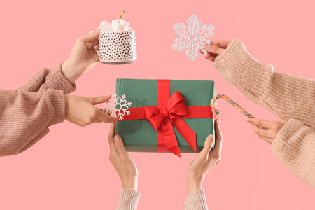 Female hands with Christmas gift, snowflakes, candy cane and cup of cocoa drink on color backgroundの写真素材