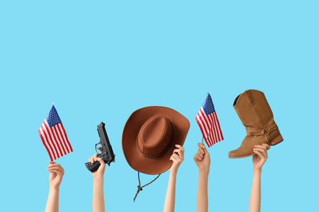 Female hands with cowboy hat, shoe, gun and flags of USA on color backgroundの写真素材