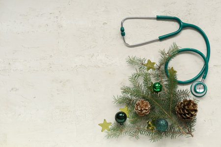 Stethoscope with Christmas tree branches, balls and cones on light backgroundの写真素材