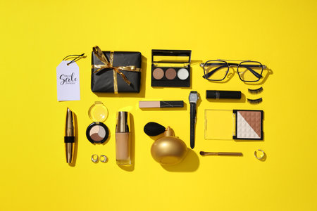 Composition with different decorative cosmetics, gift box and sale tags on yellow backgroundの写真素材