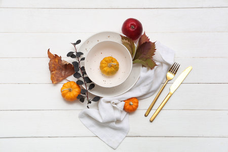 Beautiful table setting with pumpkins and autumn leaves on white wooden backgroundの写真素材